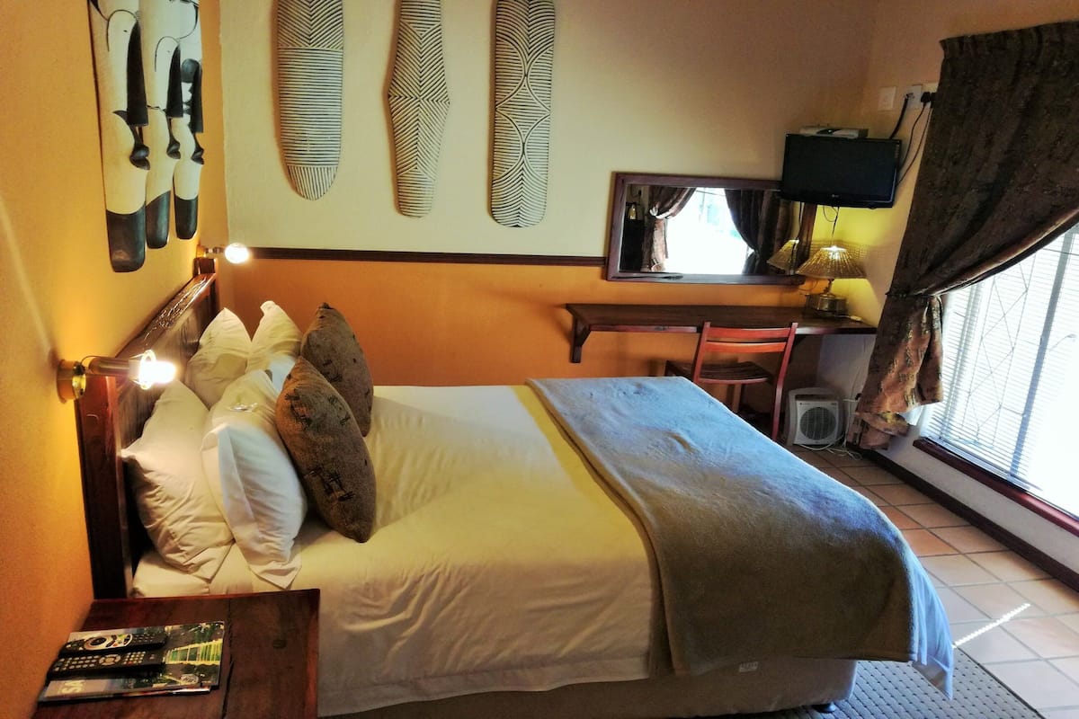 Een hotelkamer met een bed, een bureau, een televisie en een raam met gordijnen.