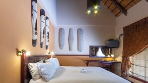 Een hotelkamer met een bed, een bureau, een televisie en wanddecoratie.