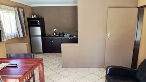 Een knus woongedeelte met een kitchenette, een eettafel en een bank.