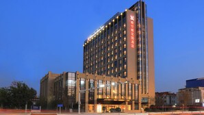 Un hotel moderno con un letrero llamativo, varios pisos y una fachada bien iluminada.