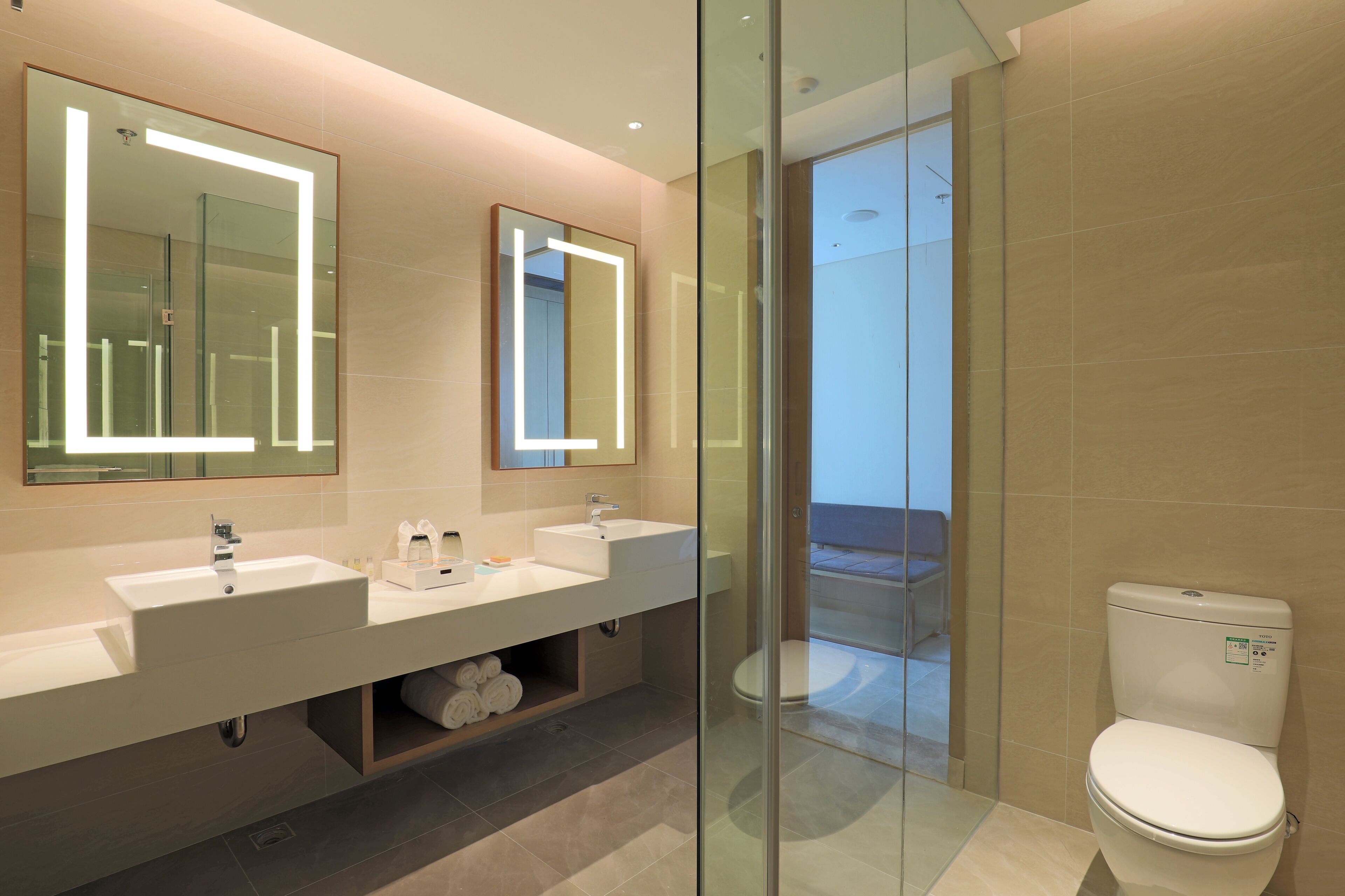 A modern bathroom with two sinks, a glass shower enclosure, and a toilet.
