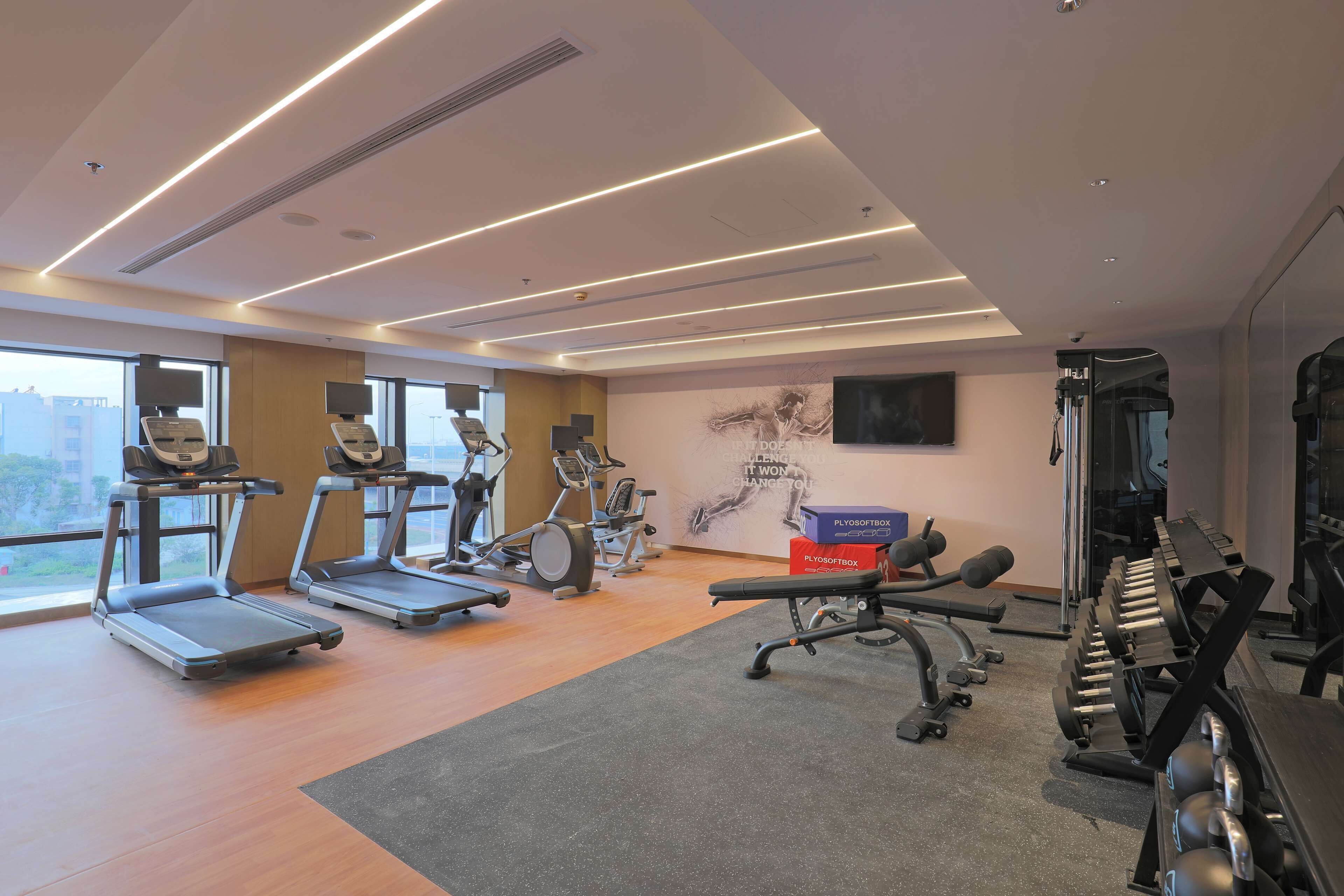 Une salle de sport équipée de tapis de course, d’appareils de musculation et d’haltères.