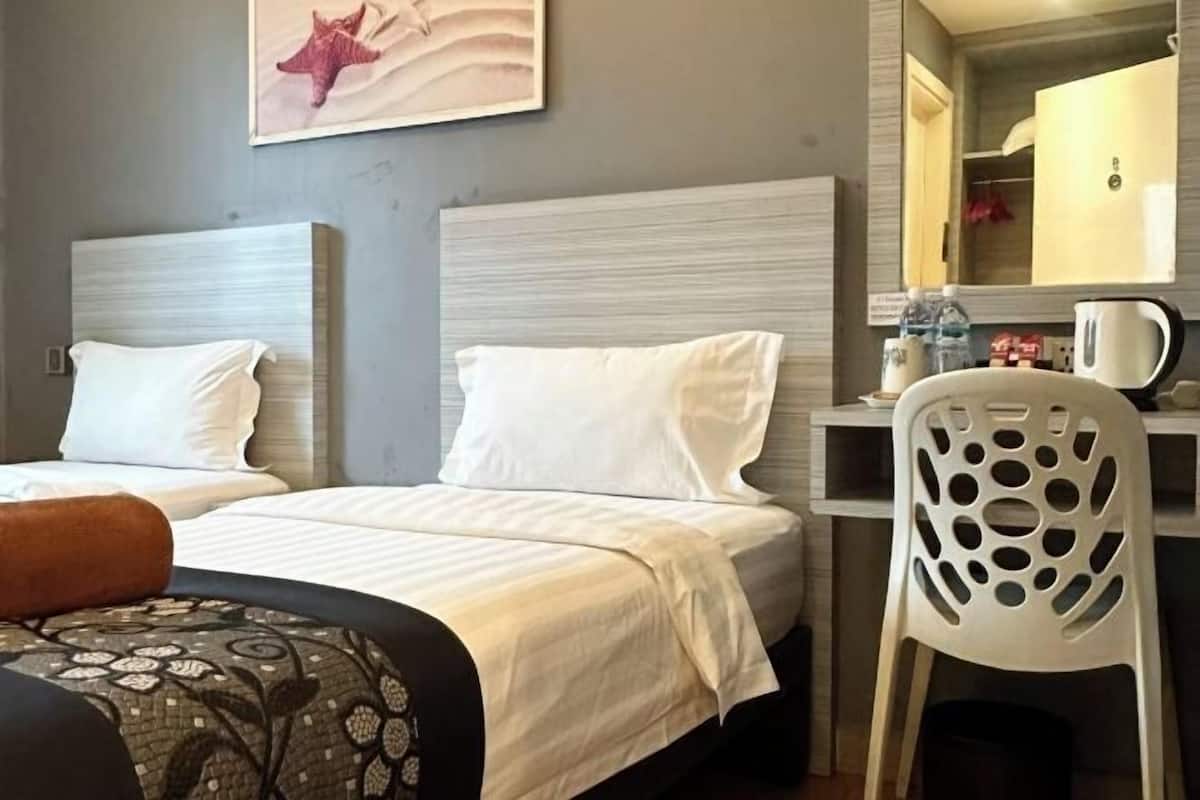 A hotel room with two beds, a desk, a chair, and a painting on the wall.