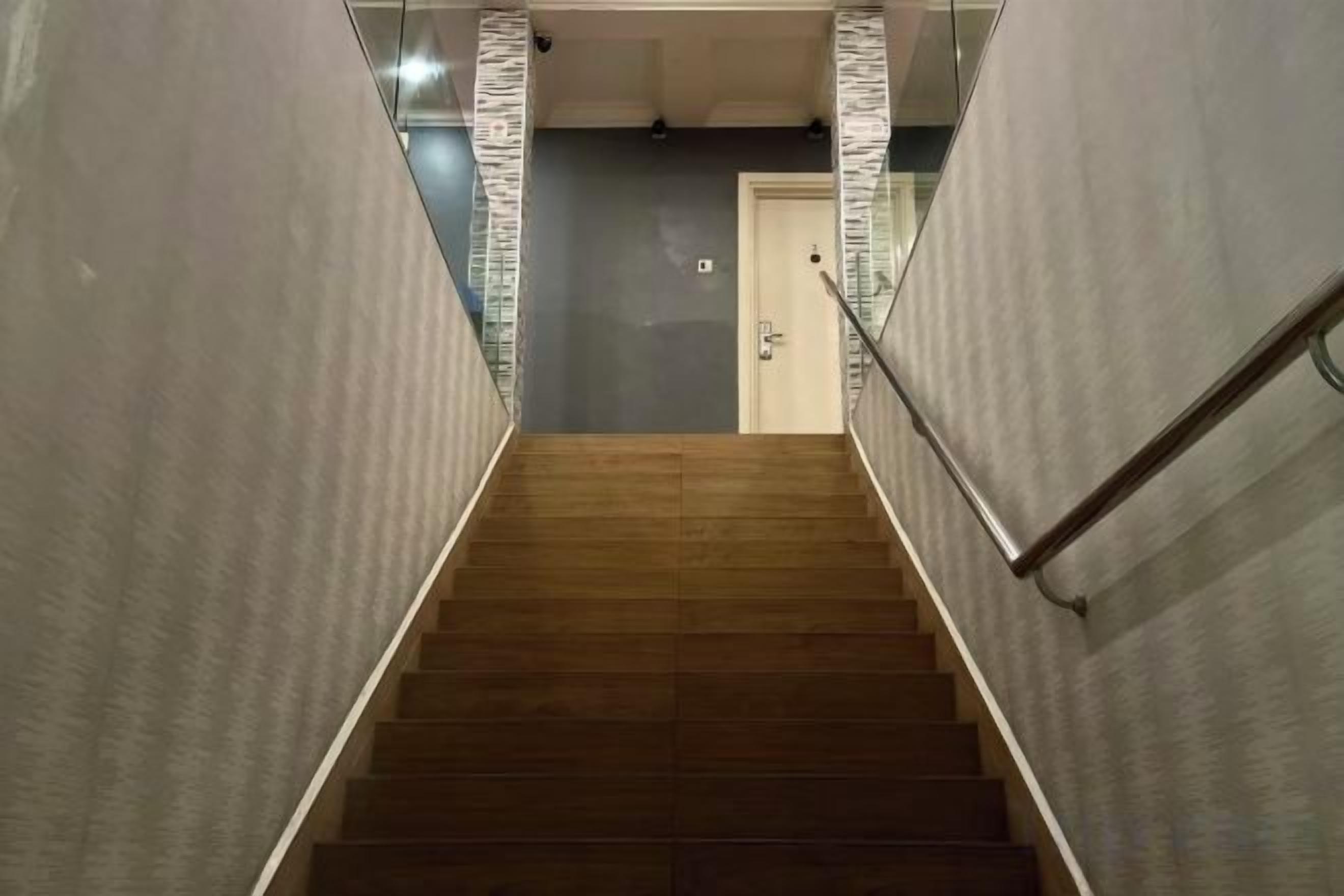 A staircase with a handrail, leading to a door at the top.