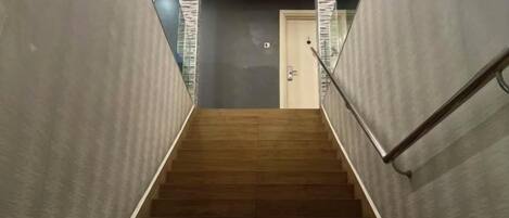 A staircase with a handrail, leading to a door at the top.