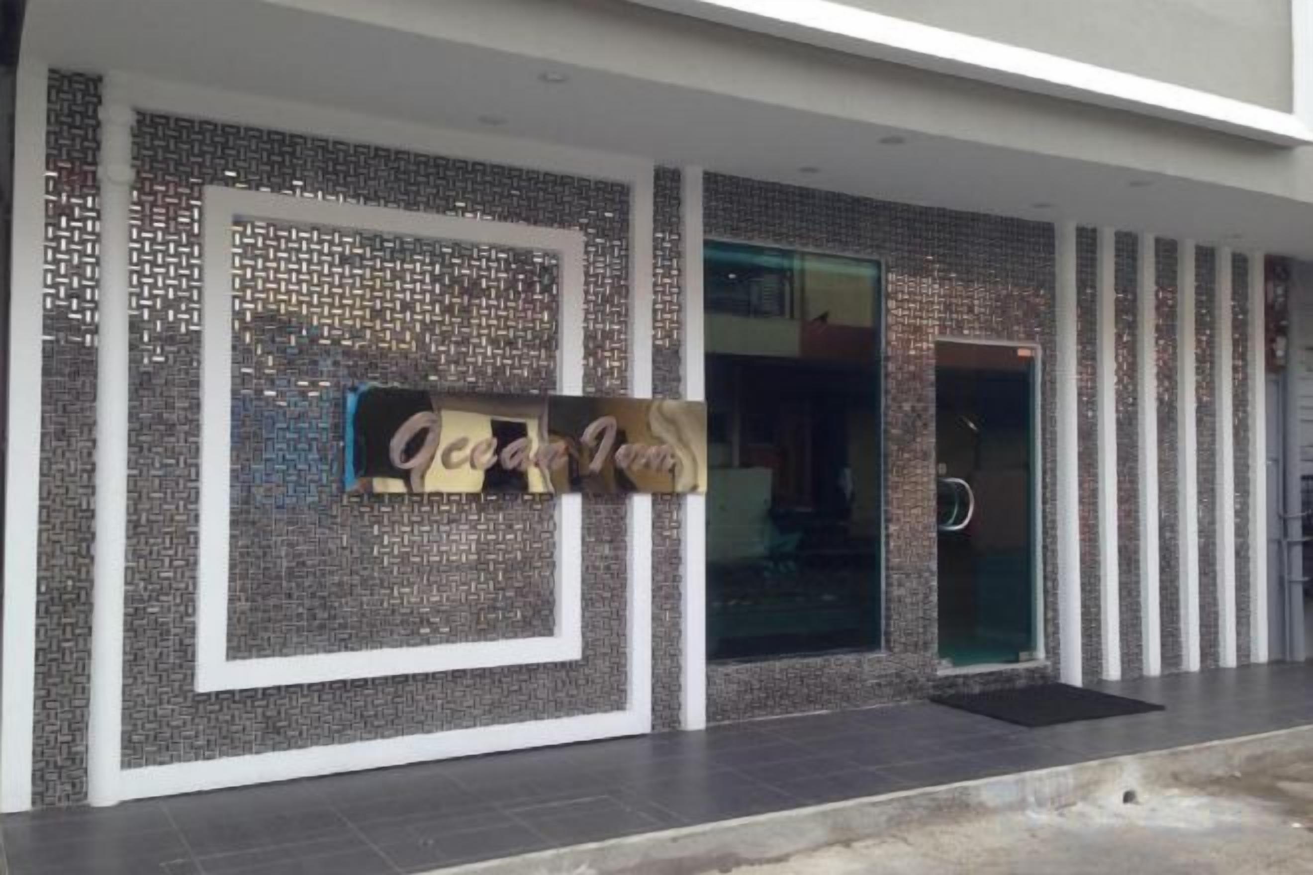 A hotel entrance with a tiled facade and a sign that reads 'Ocean Inn.'