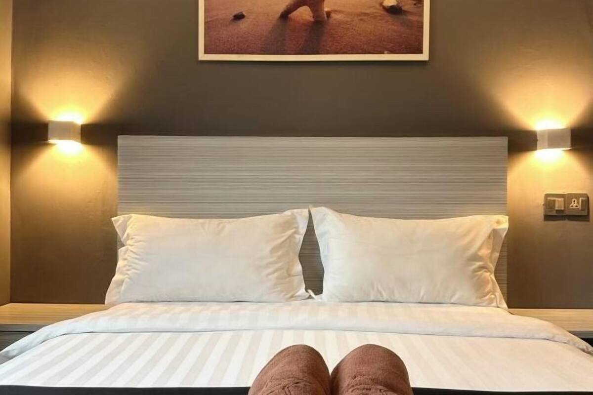 A bed with white bedding, two pillows, and a headboard.