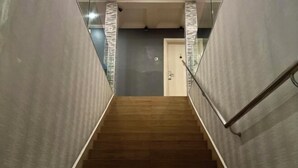 Eine Treppe mit Holzboden und Glasgeländern, die zu einer Tür am oberen Ende führt.