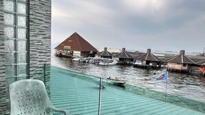 Ein verglaster Balkon mit Blick auf Bungalows auf Stelzen und einen Bootsanleger.