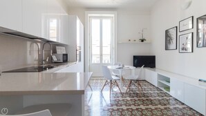 Une cuisine moderne dotée d’un grand îlot central, de meubles blancs et d’un sol à motifs.