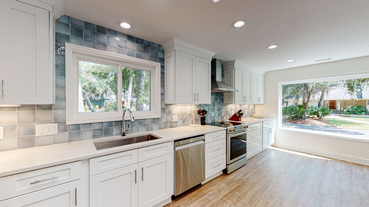 A modern kitchen with white cabinets, a large window, and a view of the outdoors.