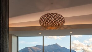Een moderne woonkamer met een groot raam, een bank, een trommel en een hanglamp.