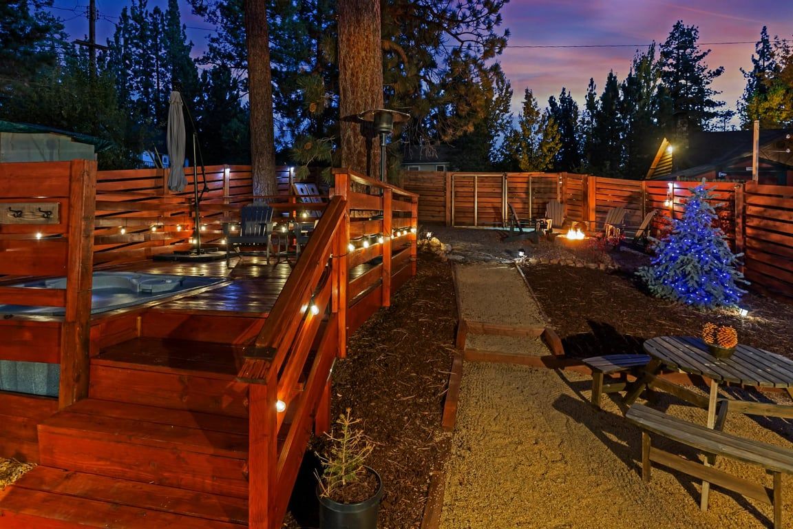A wooden deck with a fire pit, outdoor seating, and a Christmas tree.