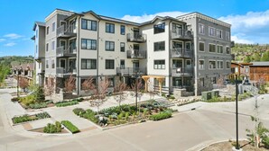 A multi-story residential building with balconies, a landscaped courtyard, and a clear view of the surrounding area.