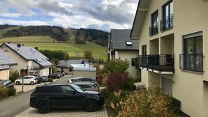 A residential building with a parking area, a view of a hill, and a clear sky. - Panorama Lounge (Willingen)