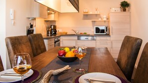 A dining table set with plates, cutlery, and a bowl of fruit. - Panorama Lounge (Willingen)