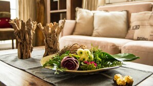A living room with a sofa, a coffee table with a decorative arrangement including a plate with flowers and a bird nest, and a wooden sculpture. - Panorama Lounge (Willingen)