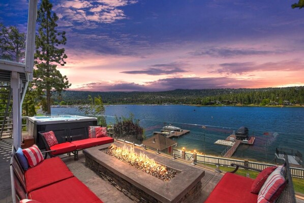 A patio with outdoor seating and a fire feature overlooking a lake.