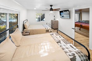 Un dormitorio con dos camas, ventilador de techo, televisor y mesa de billar.
