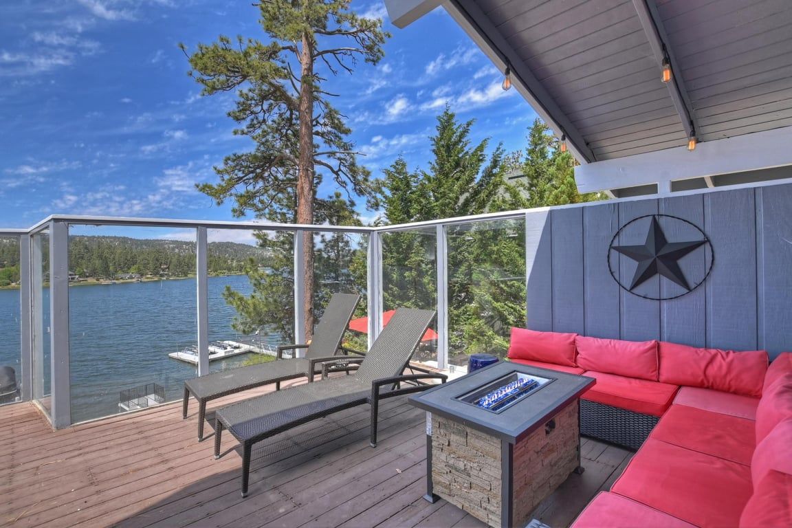 Eine Terrasse mit Gartenmöbeln, einem Feuerkorb und Blick auf einen See.