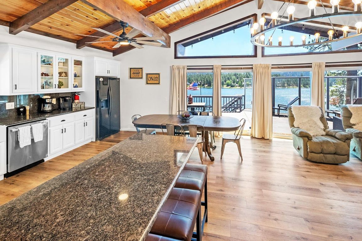 Een ruime keuken met een groot eiland, houten vloeren en uitzicht op een terras.