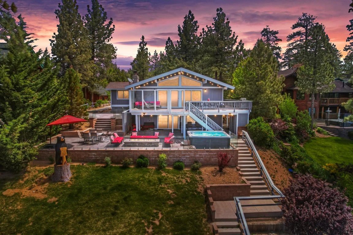 Une maison à deux étages dotée d’une terrasse, d’un espace salon extérieur et d’un jacuzzi.