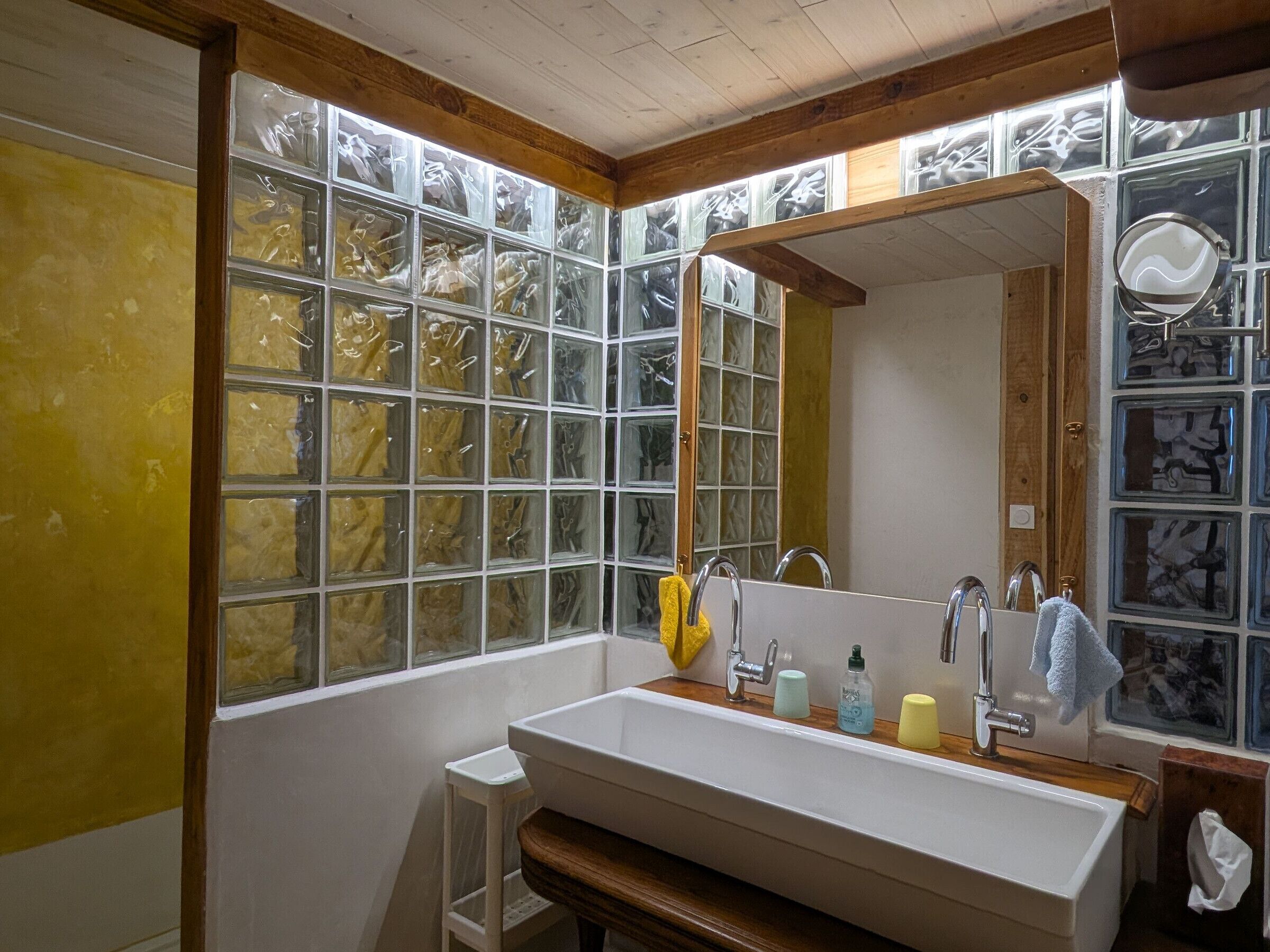 A bathroom with a large window, a sink, and a mirror.