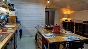 A cozy kitchen with wooden walls, a dining area with a table set for two, and a skylight above.