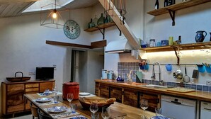 A modern kitchen with wooden cabinets, a dining table set for six, and a variety of kitchen utensils and appliances.