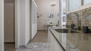 A modern kitchen with a large island, a chandelier, and a patterned backsplash. - Modern & quiet apartment in typical Sevilla house (Sevilla)