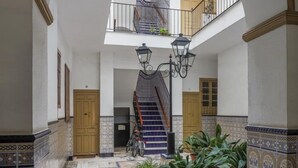 A spacious courtyard with a central staircase, potted plants, and a bicycle. - Modern & quiet apartment in typical Sevilla house (Sevilla)