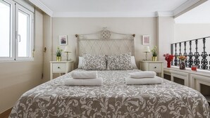 A bedroom with a large bed, two bedside tables with lamps, a decorative headboard, and a window with a view. - DUPLEX DREAMS OF SEVILLE A QUALITIES PARKING (Sevilla)