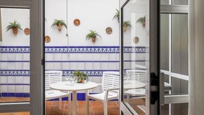 A dining area with white chairs and a round table, blue and white tiled walls, and potted plants. - DUPLEX DREAMS OF SEVILLE A QUALITIES PARKING (Sevilla)