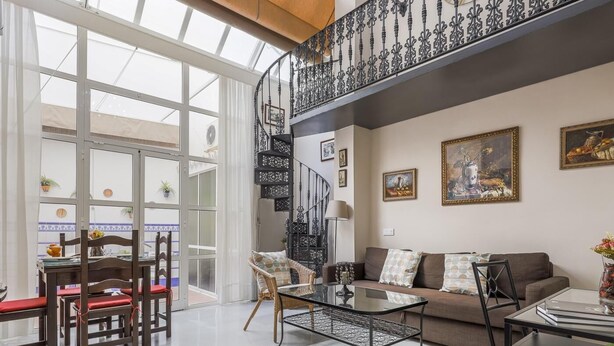 A spacious living area with a high ceiling, a staircase, and a balcony. - DUPLEX DREAMS OF SEVILLE A QUALITIES PARKING (Sevilla)