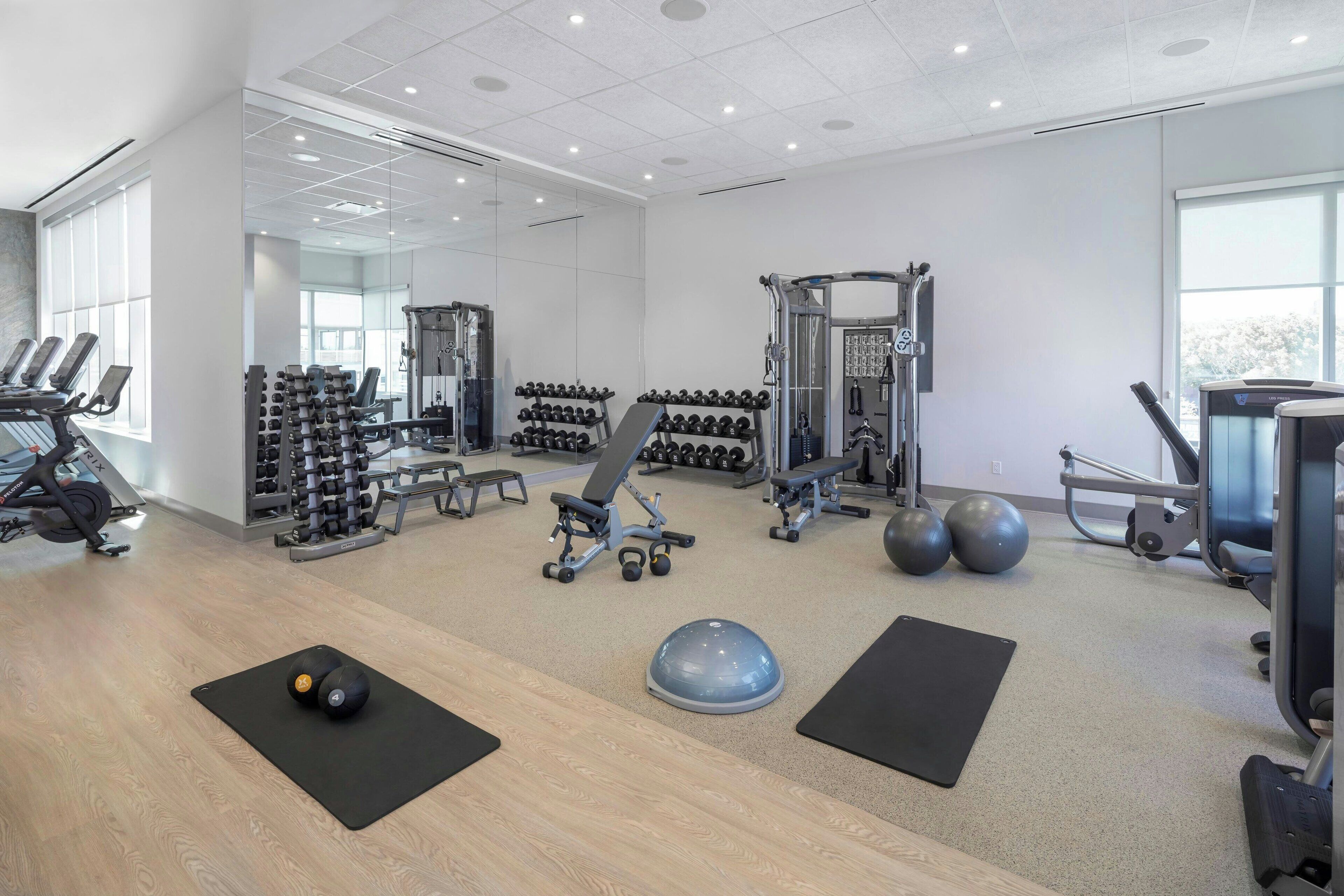 Un gimnasio con equipo de ejercicio, estantes para pesas y pelotas de ejercicio.