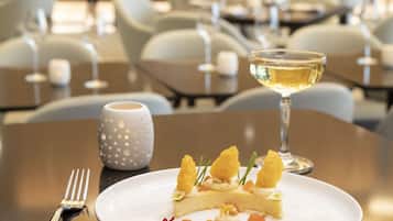 Una mesa de comedor con un plato de comida, una copa de vino blanco y un tenedor.