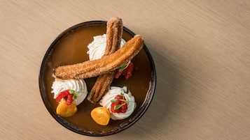 A dessert plate with churros, whipped cream, and fruit garnishes.