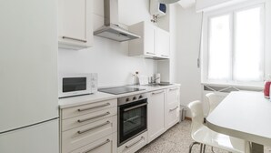 Een moderne keuken met witte kasten, een magnetron, een fornuis en een spoelbak.