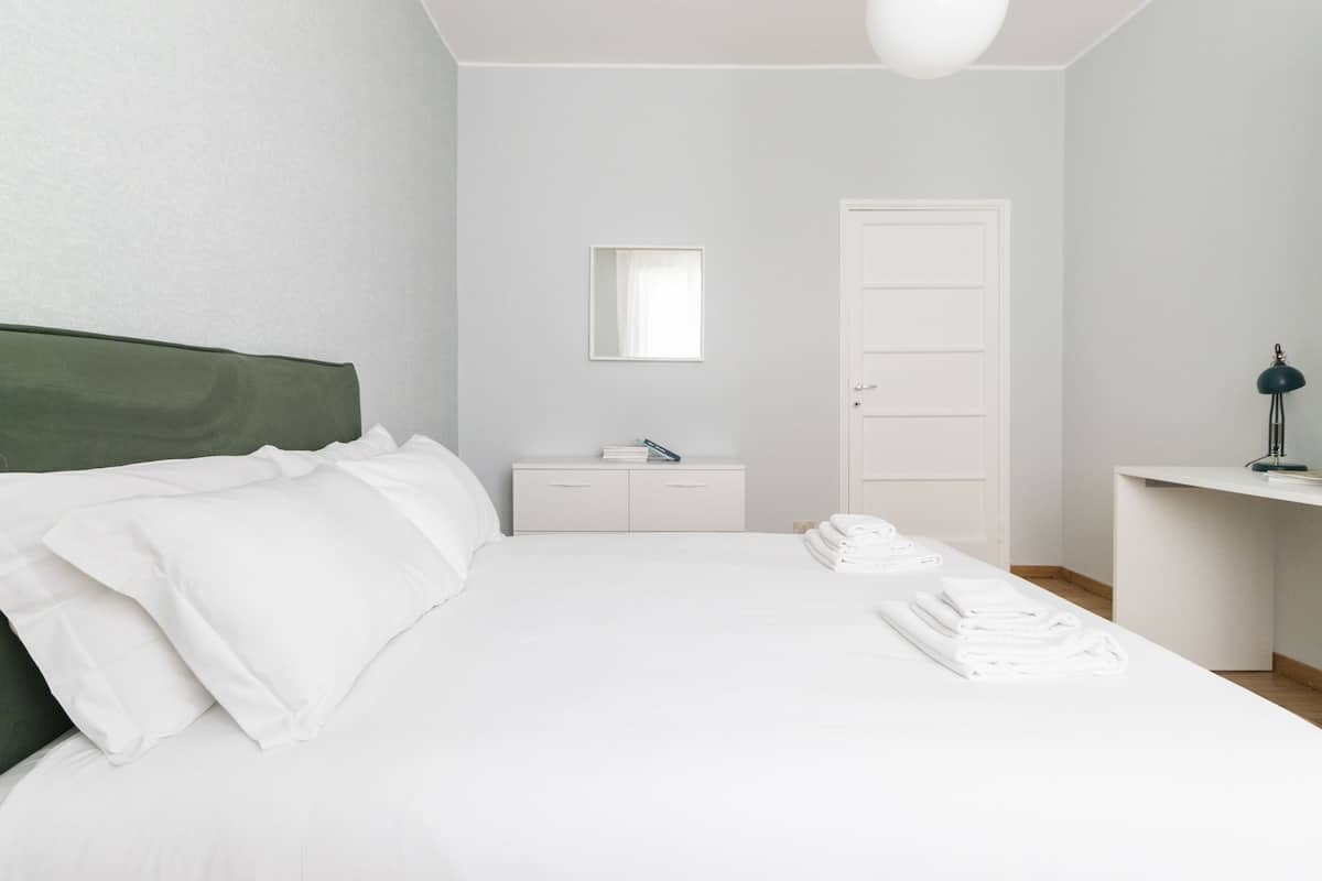 A bedroom with a bed, a dresser, a mirror, and a door.