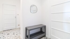 Een gang met witte deuren, een klein grijs console tafeltje en een spiegel aan de muur.