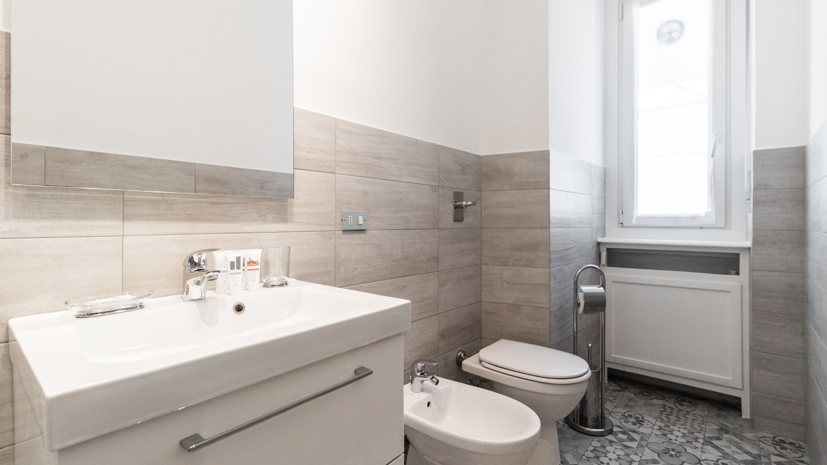 A modern bathroom with a white sink, a bidet, and a toilet.