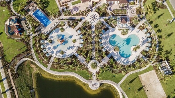 Vue aérienne d’un complexe hôtelier doté de plusieurs piscines, de palmiers et d’une fontaine centrale.