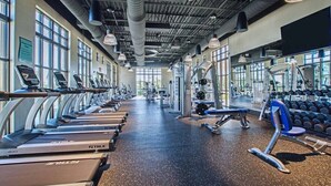 Une salle de sport équipée de tapis de course, d’appareils de musculation et d’haltères.