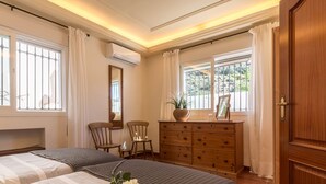 Ein Schlafzimmer mit zwei Betten, einem Schminktisch, einem Spiegel und einem Fenster mit Vorhängen.