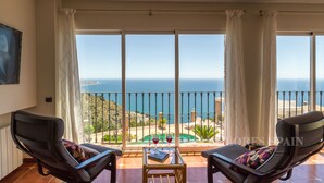 Ein Balkon mit zwei Stühlen und einem Tisch mit Blick auf die Küste.
