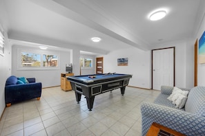 Una habitación con mesa de billar, dos sofás y una puerta.