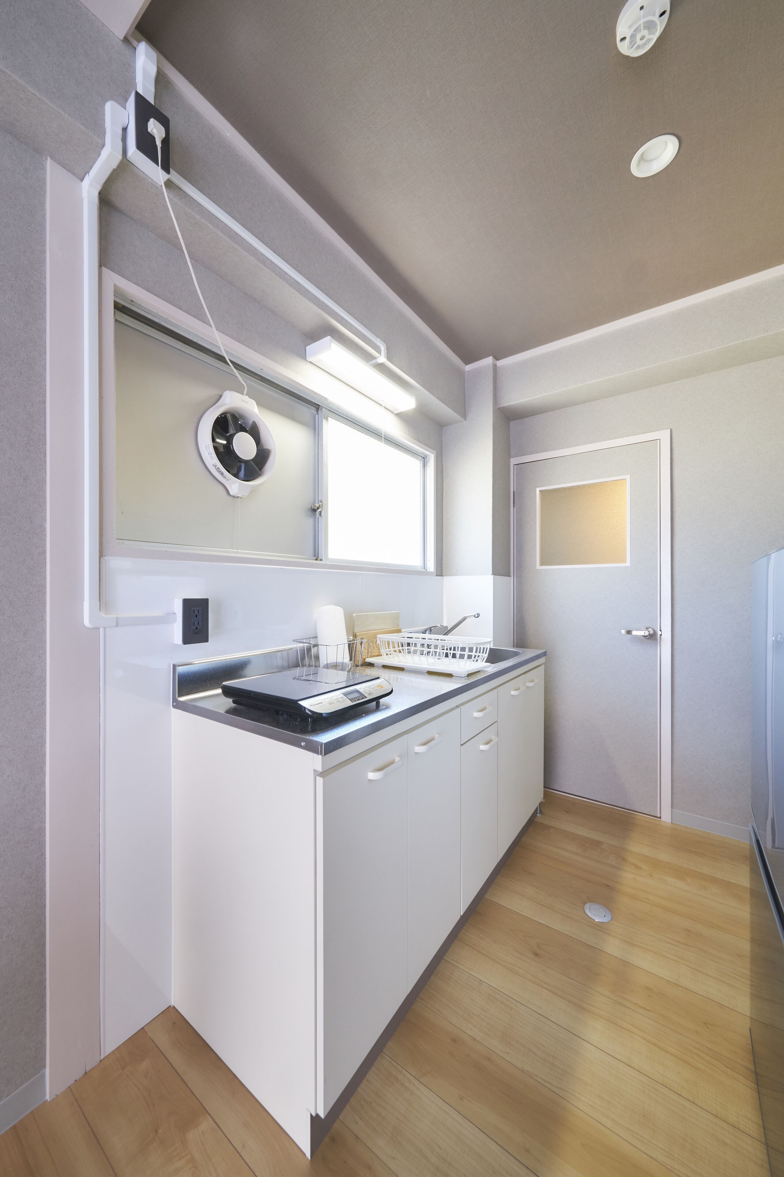 A modern kitchen with white cabinetry, a built-in oven, and a window above the sink.