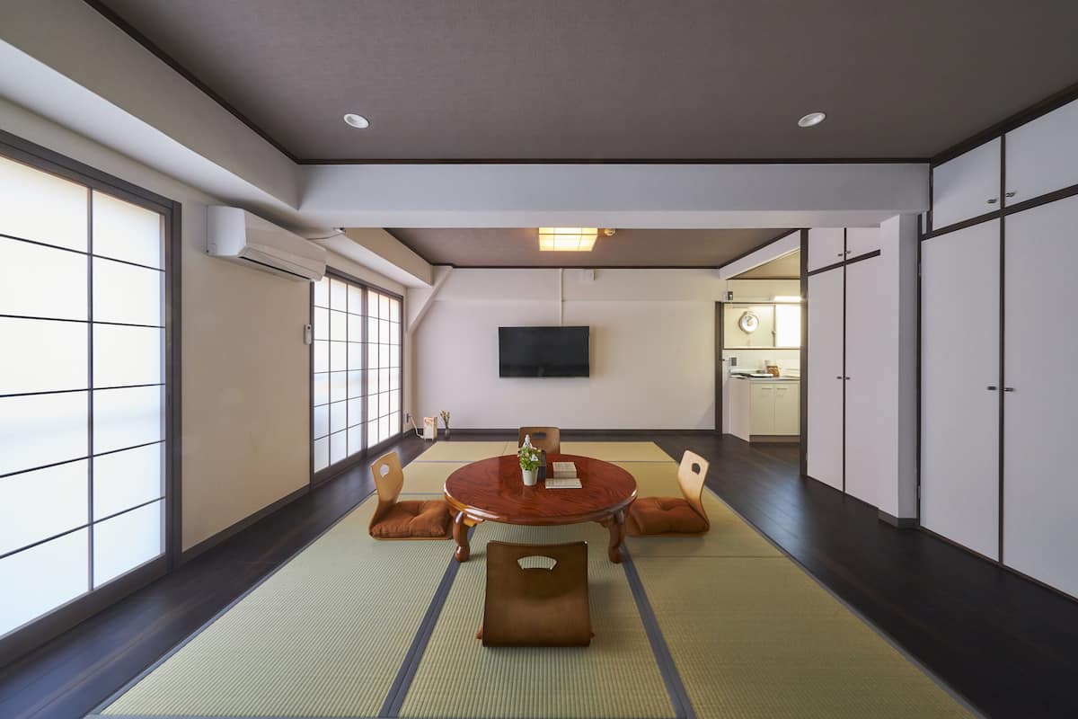 A traditional Japanese-style room with tatami flooring, a tatami mat table, and shoji screens.