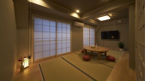 Une pièce de style japonais traditionnel, avec un sol recouvert de tatamis, une table faite de tatamis, une petite table basse et des portes coulissantes.