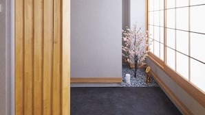 Une pièce avec un plancher en bois, une porte coulissante, une fenêtre à carreaux et une petite plante.